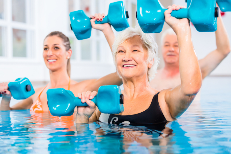 Senior on the pool holding dumbbells